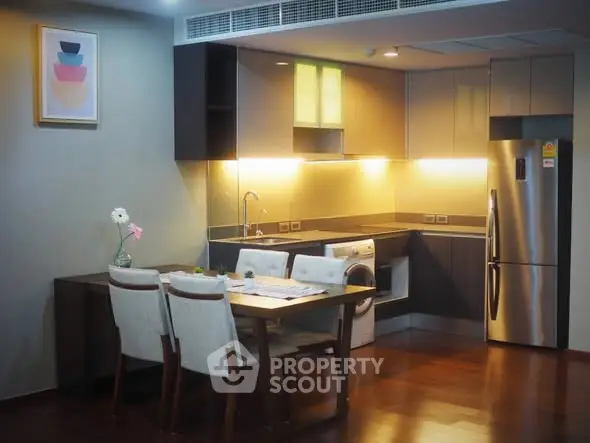 Modern kitchen with dining area, featuring stainless steel appliances and elegant lighting.
