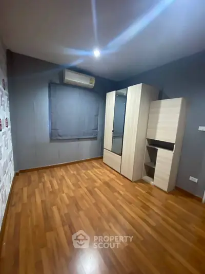 Spacious bedroom with wooden flooring and modern wardrobe, ideal for cozy living.