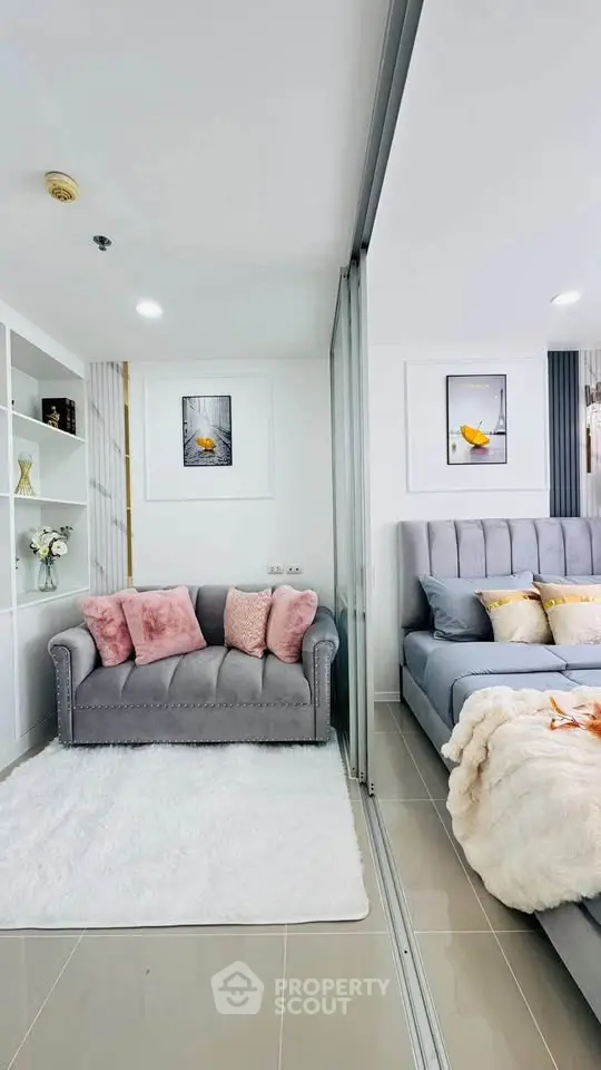 Modern living room with cozy sofa and elegant bedroom separated by glass partition.
