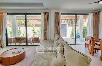 Spacious living room with large windows and garden view, featuring modern furniture and elegant decor.