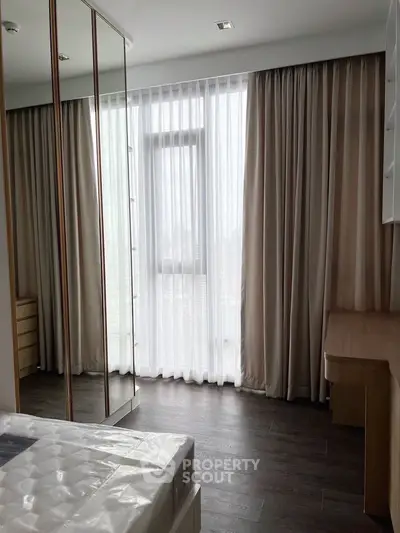 Spacious bedroom with floor-to-ceiling window and elegant curtains