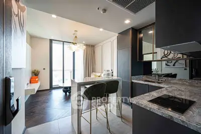 Modern kitchen with sleek design, marble countertops, and open layout leading to a bright dining area with balcony view.