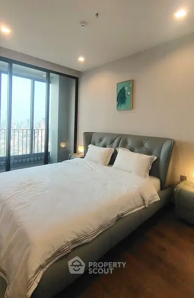 Luxurious bedroom with city view and elegant decor, featuring a plush bed and floor-to-ceiling windows.