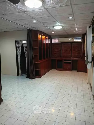 Spacious room with built-in wooden shelves and tiled flooring, ideal for versatile living space.