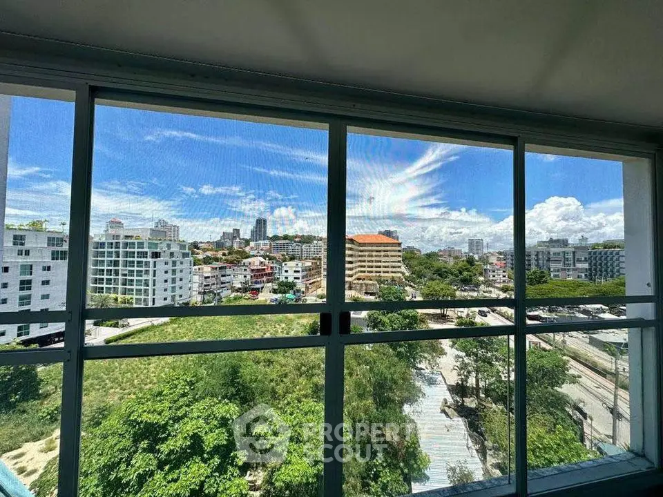 Stunning cityscape view from high-rise apartment window with lush greenery and vibrant skyline.
