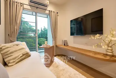 Cozy living room with modern decor, large TV, and balcony view