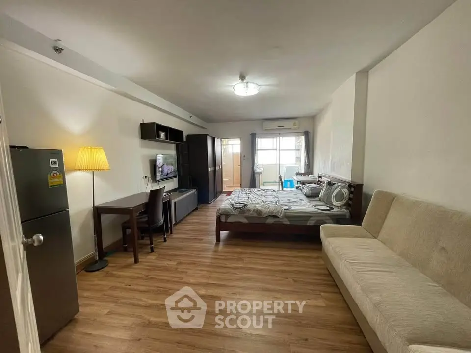 Spacious studio apartment with modern furnishings and wooden flooring, featuring a cozy living area and natural light.