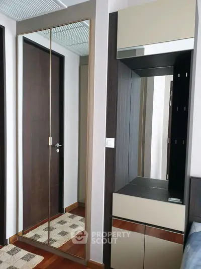 Modern bedroom with mirrored wardrobe and sleek wooden flooring