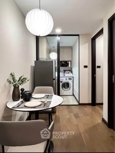 Modern dining area with adjacent kitchen featuring washing machine and sleek appliances.