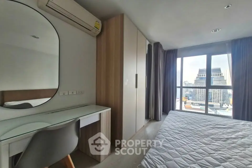 Modern bedroom with city view, featuring a stylish desk and large window.
