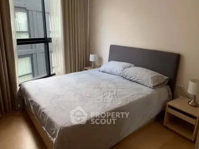 Cozy bedroom with large window and modern decor in urban apartment.