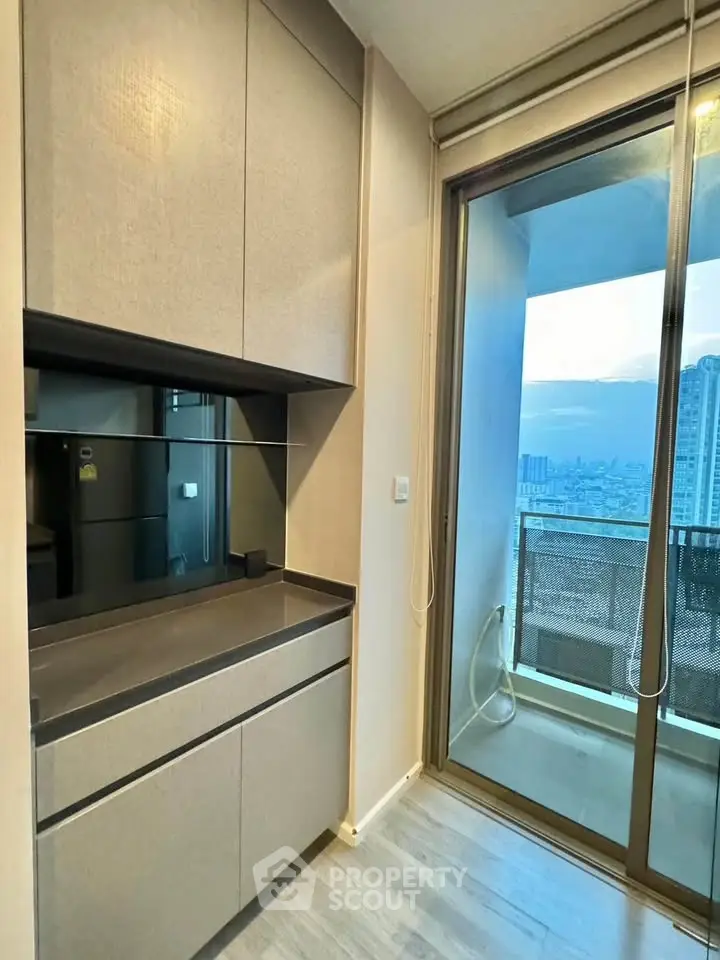 Modern kitchen with sleek cabinetry and balcony view in high-rise apartment
