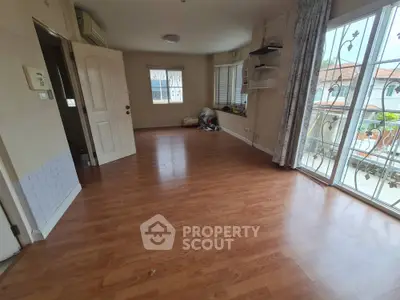 Spacious empty room with wooden flooring and large windows in a residential property
