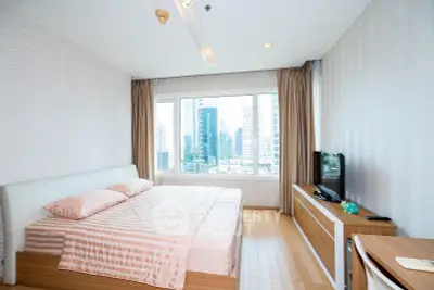 Modern bedroom with city view, featuring a cozy bed and sleek furniture.