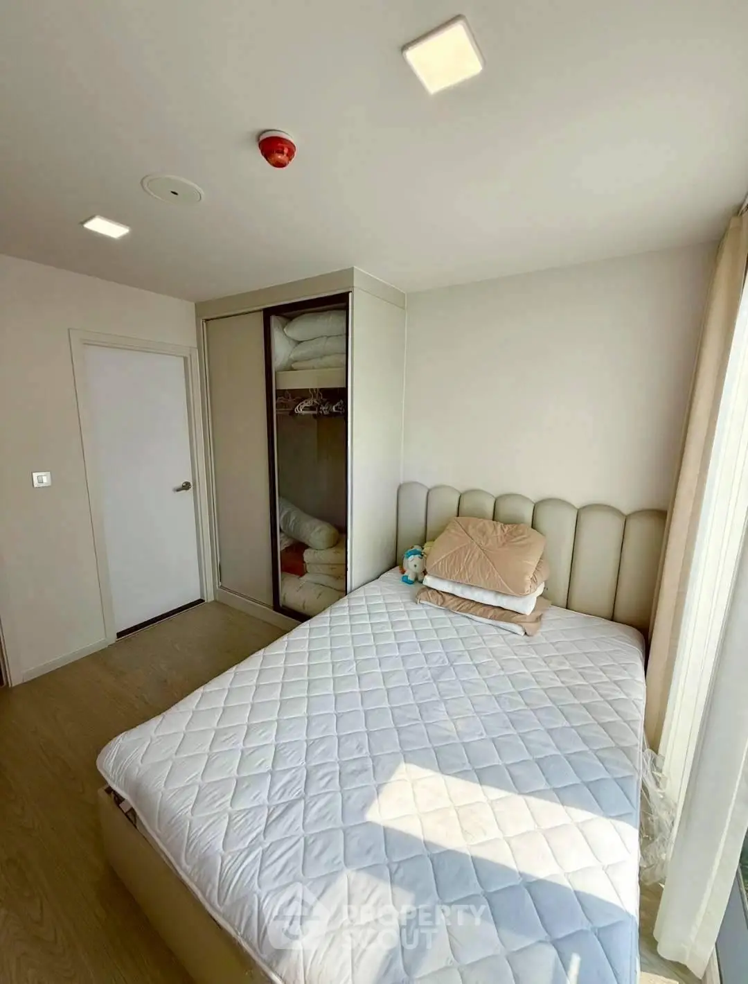 Cozy bedroom with modern design and ample natural light, featuring a comfortable bed and built-in wardrobe.