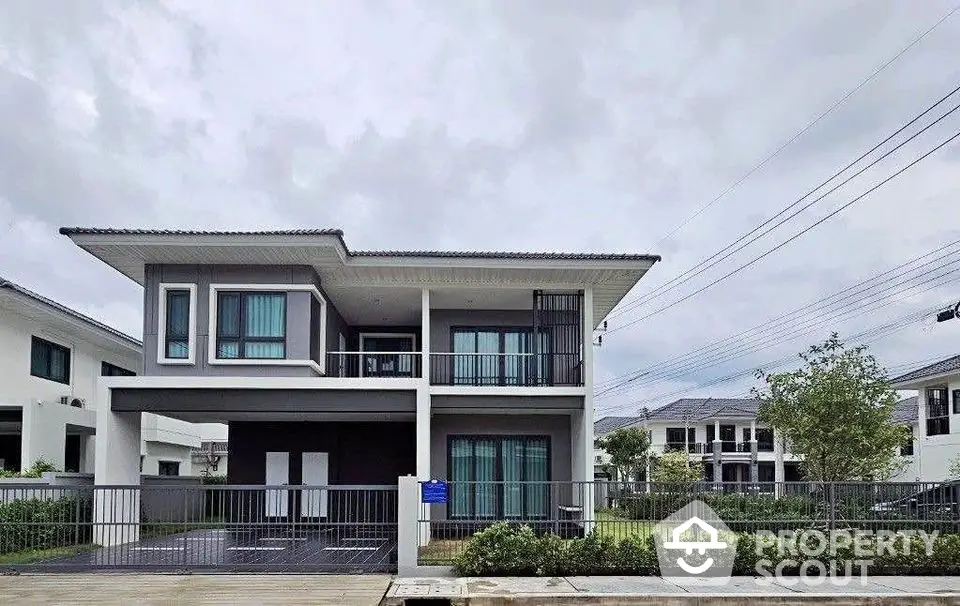 Modern two-story house with sleek design and spacious balcony in a serene neighborhood.