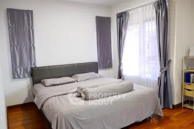 Cozy bedroom with elegant gray curtains and wooden flooring, perfect for relaxation.