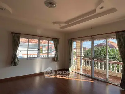 Spacious sunlit room with large windows and elegant curtains, perfect for a cozy living space.