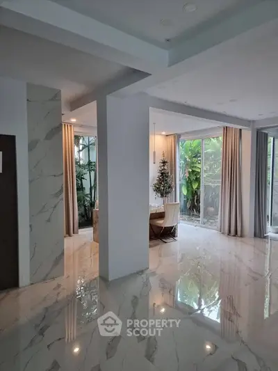 Elegant modern living space with marble flooring and lush garden view.