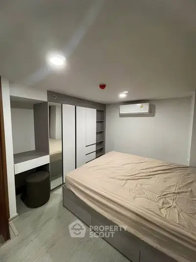 Modern bedroom with sleek design, featuring built-in wardrobe and air conditioning unit.