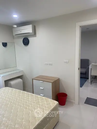 Modern bedroom with minimalist decor and adjacent dining area, featuring air conditioning and ample natural light.