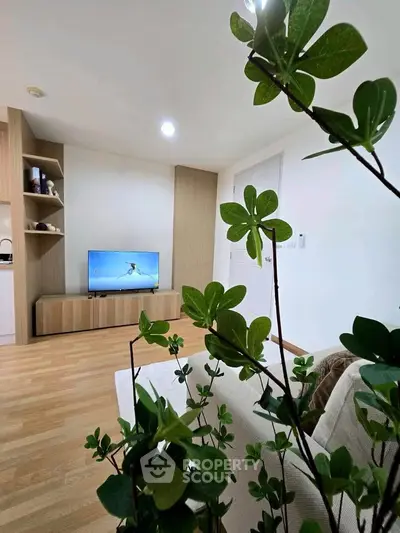 Modern living room with stylish decor and flat-screen TV, featuring elegant wooden flooring and contemporary shelving.