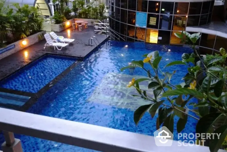 Inviting residential complex pool with ambient lighting and lush greenery, perfect for evening relaxation and social gatherings.