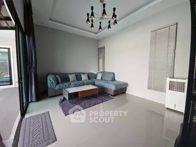 Modern living room with stylish chandelier and cozy sectional sofa, perfect for relaxation and entertaining.