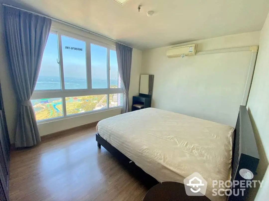 Spacious bedroom with large windows offering a stunning ocean view, ample natural light, and a serene atmosphere perfect for relaxation.