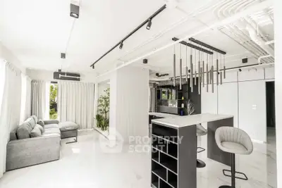 Modern open-layout living room with sleek design and stylish bar area, featuring contemporary lighting and large windows.