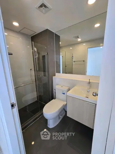 Modern bathroom with glass shower and sleek fixtures in contemporary apartment.
