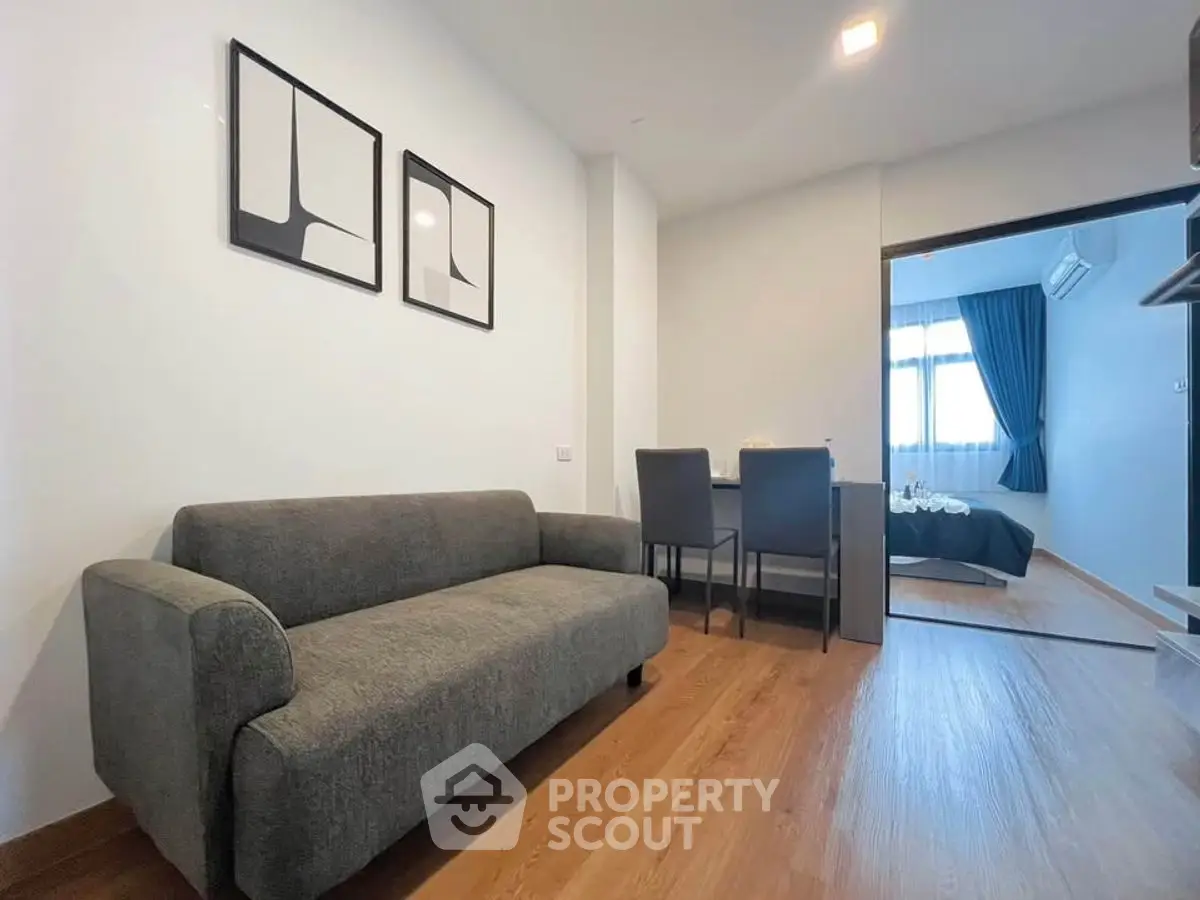 Modern living room with gray sofa and dining area in open layout apartment.