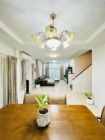 Spacious living room with elegant chandelier and modern decor, perfect for family gatherings.