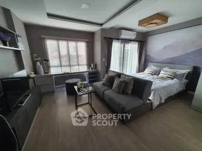 Modern bedroom with stylish decor and natural light, featuring a cozy bed and seating area.