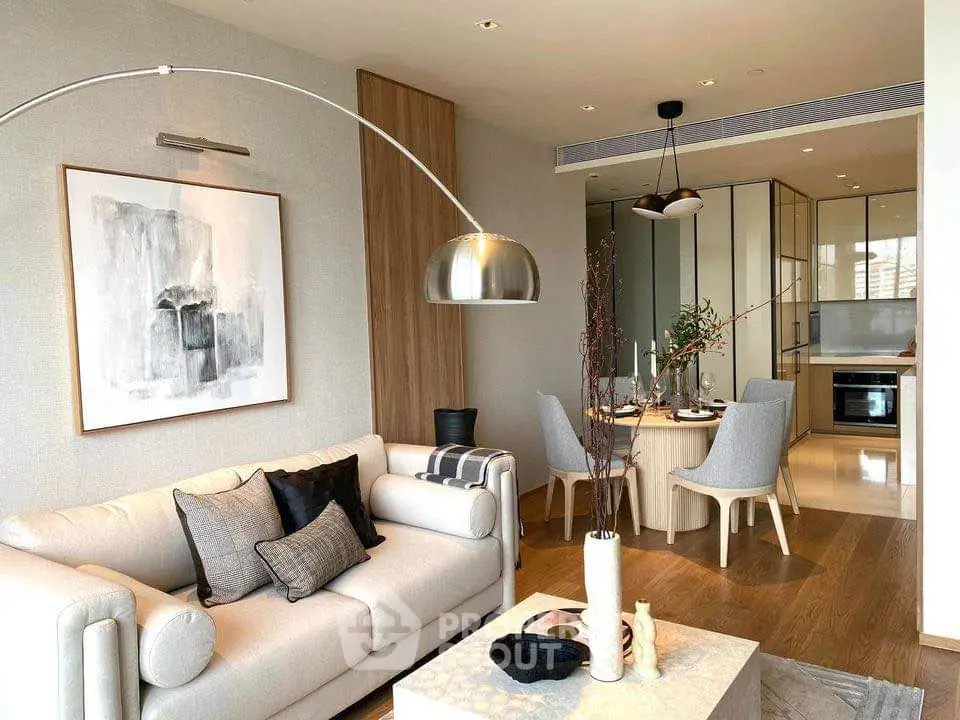 Modern living room with elegant decor and open kitchen layout, featuring stylish furniture and contemporary lighting.