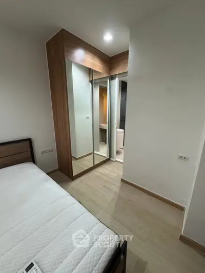 Modern bedroom with mirrored closet and ensuite bathroom in stylish apartment.