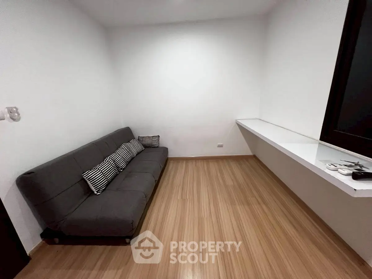 Cozy minimalist living room with sleek wooden flooring and modern gray sofa, perfect for urban living.