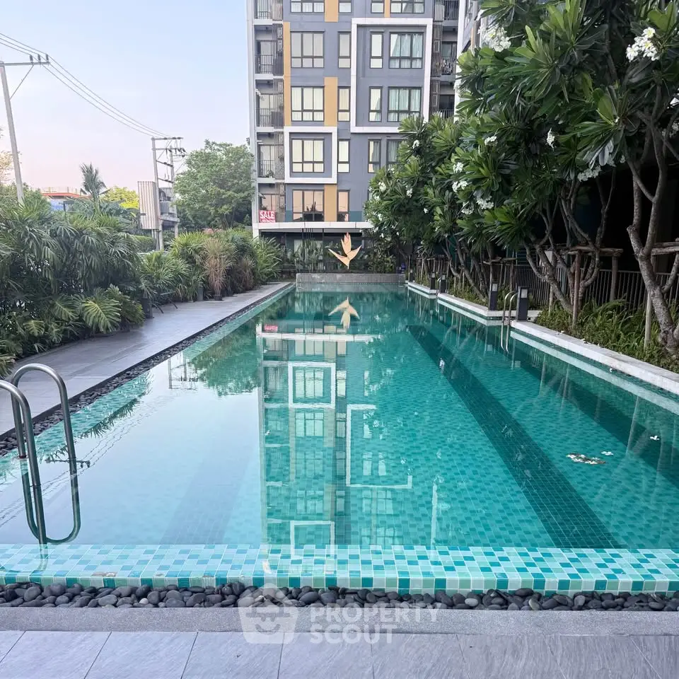 Luxurious condominium pool surrounded by lush greenery and modern architecture, perfect for relaxation and leisure.