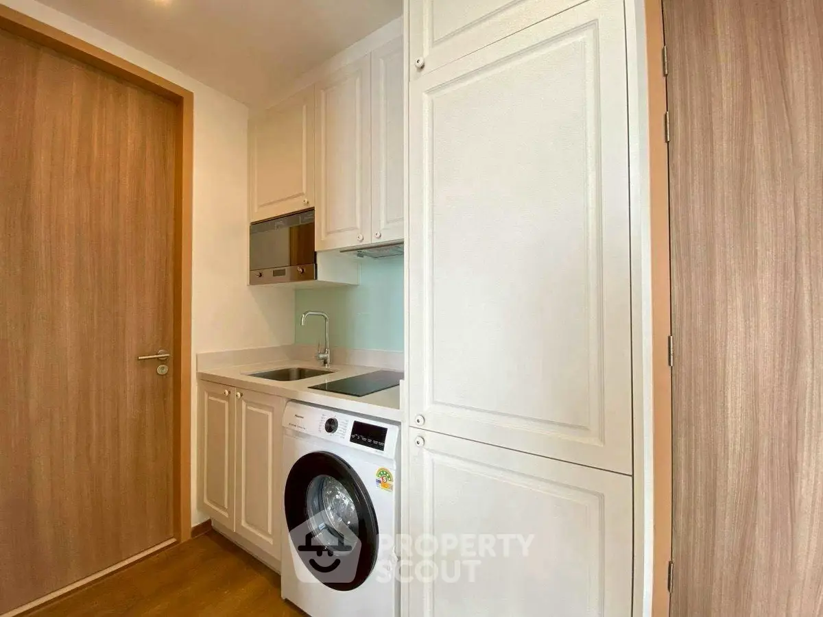 Modern kitchen with washing machine and sleek cabinetry in compact space.