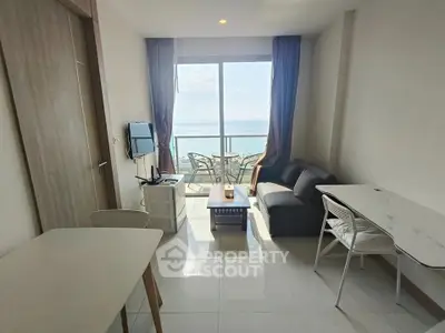 Modern living room with ocean view and balcony access in a high-rise apartment.