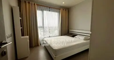 Modern bedroom with large window and minimalist decor in a high-rise apartment.