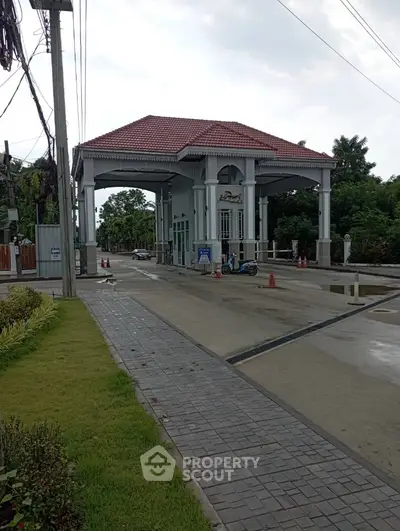 Elegant gated entrance of residential community with lush greenery and paved driveway