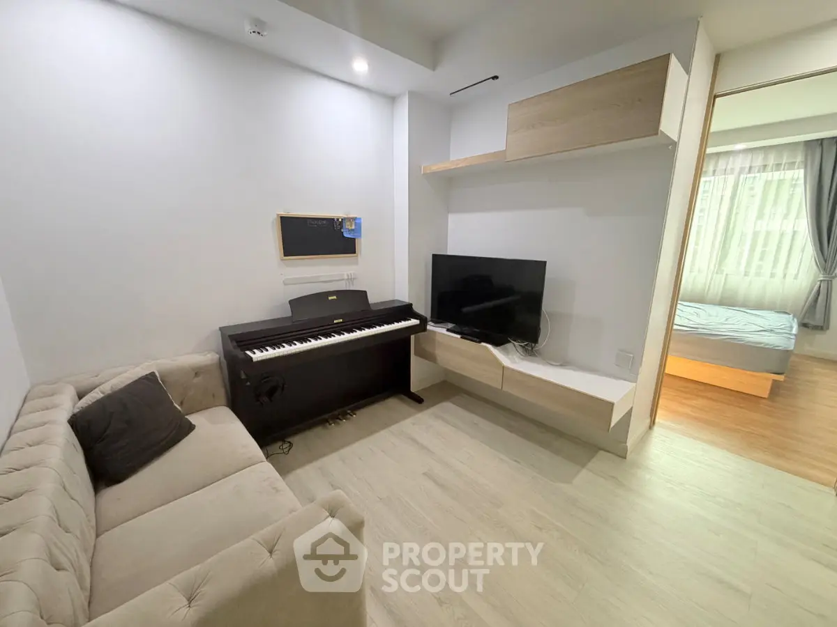 Modern living room with piano and TV, adjacent to a cozy bedroom, showcasing stylish interior design.