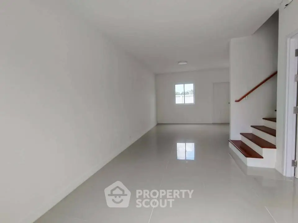 Spacious empty room with glossy floor and staircase, ready for customization.
