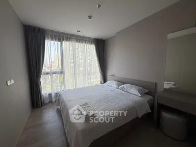 Modern bedroom with large window and elegant decor in urban apartment.