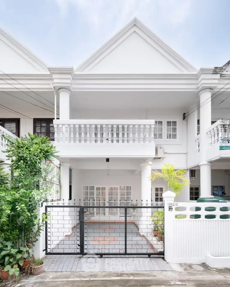 Charming white townhouse with classic columns and gated entrance, perfect for family living.