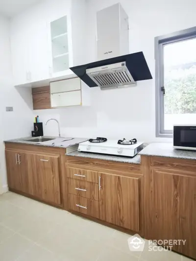 Modern kitchen with gas stove and wooden cabinets in bright apartment