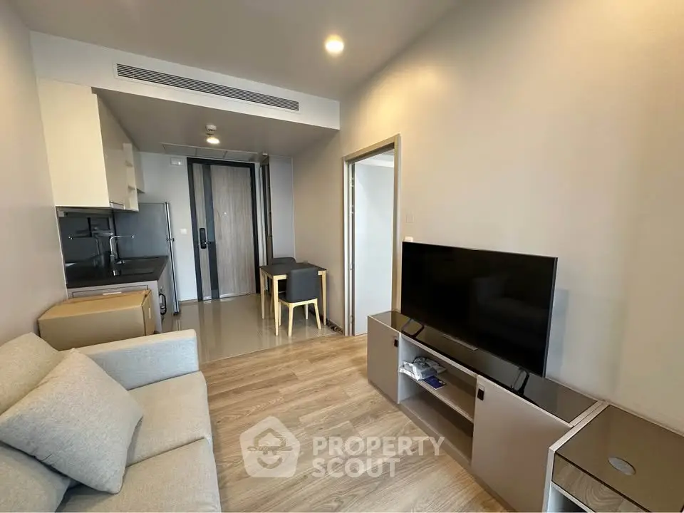 Modern living room with sleek furniture and open kitchen layout in a stylish apartment.