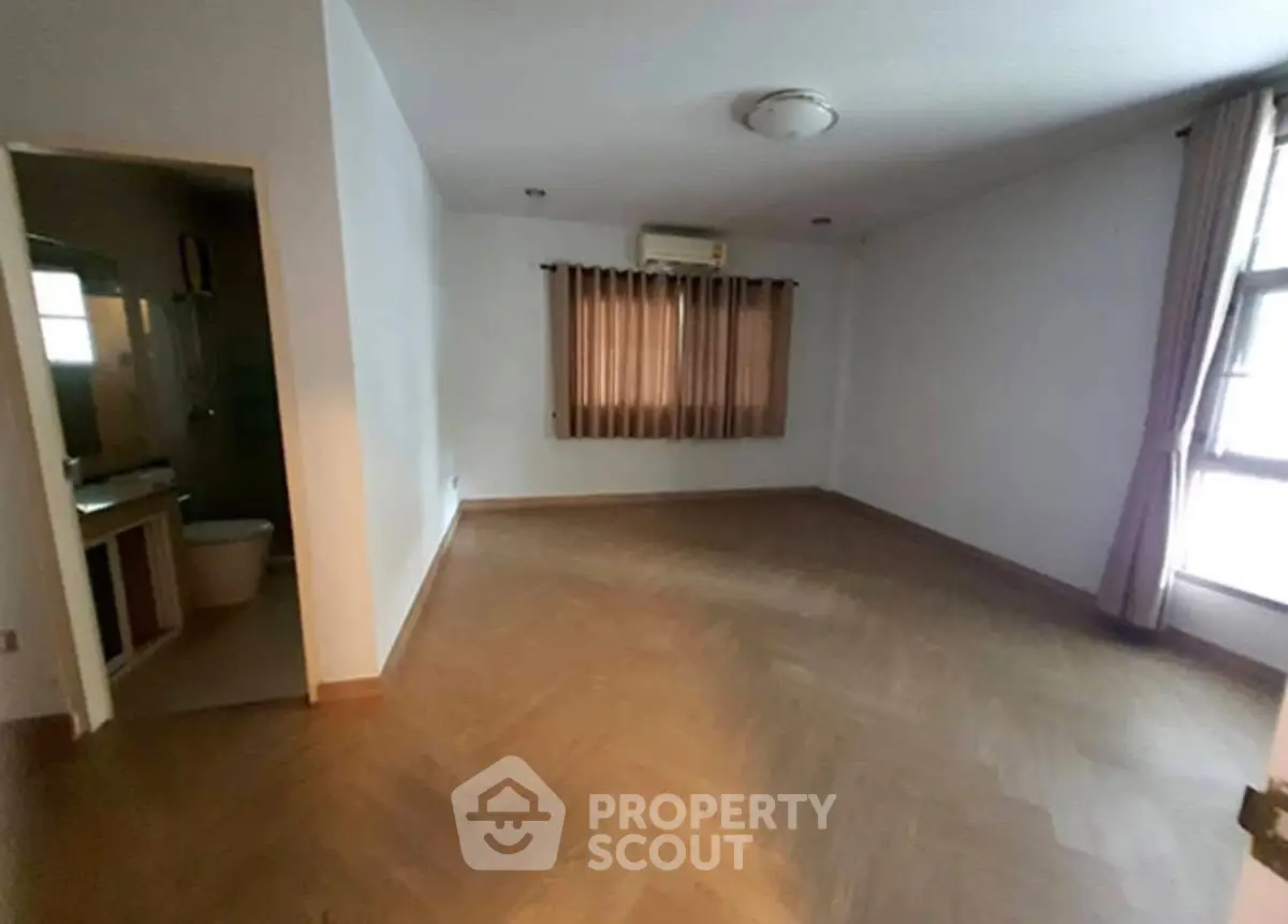 Spacious empty room with wooden flooring and natural light, ideal for customization.