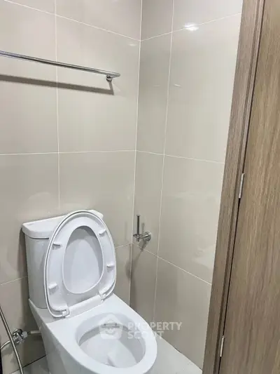 Modern bathroom with sleek toilet and neutral tile design, perfect for contemporary living.